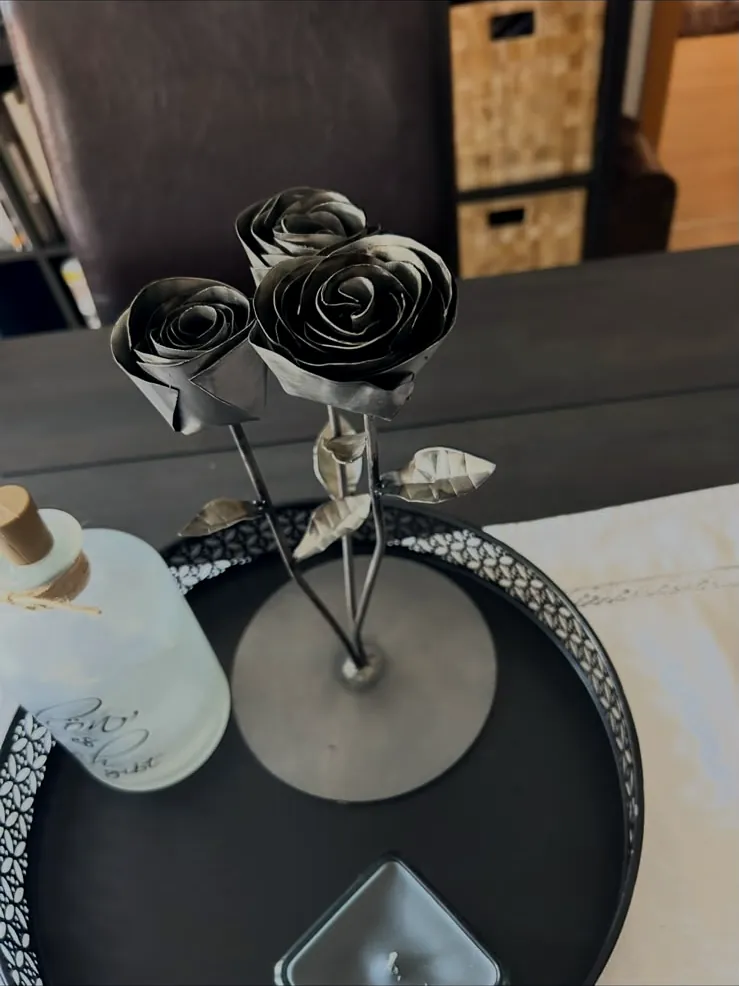 Drei handgeformte Rosen aus Stahl auf einer runden Bodenplatte