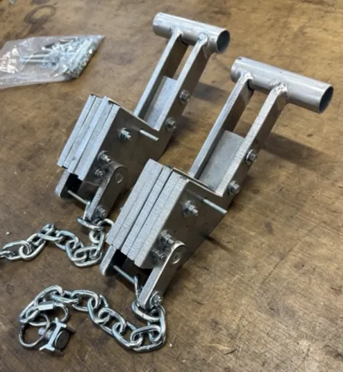 Zwei Spannvorrichtungen aus Metall mit Ketten auf einer Holzwerkbank